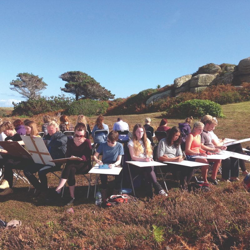 Large group of Falmouth Illustration students sitting and drawing in a circle in countryside