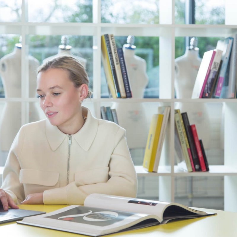 Student working at laptop in front of bookcase