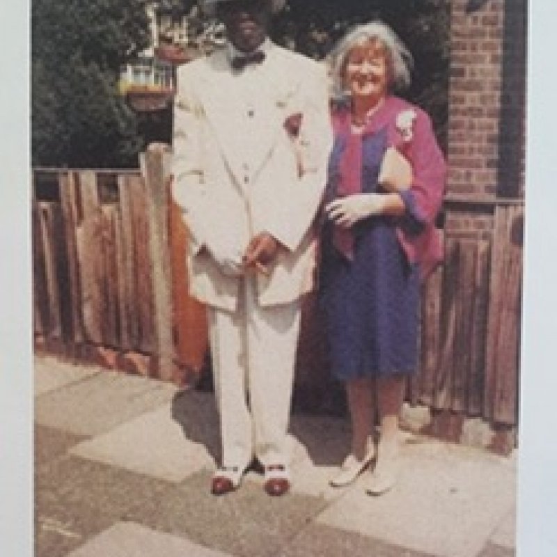Old photo of a black man (Julie Felix's dad) wearing a white suit linking arms with a white woman (Julie Felix's mum) wearing blue and burgundy dress