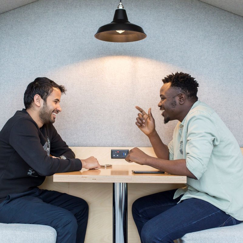 Two students talking across a table at Falmouth University