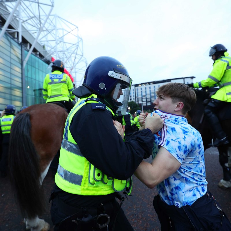 A policeman and a football fan clashing outside a football stadium 