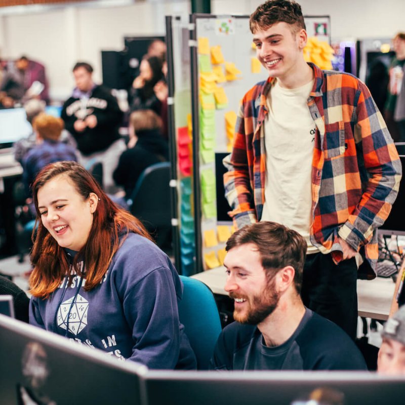 A group of games students smiling and laughing around a computer