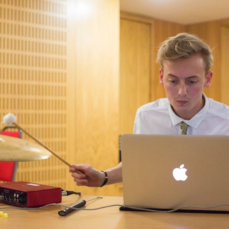 Student at laptop recording sound of a symbol being hit in Falmouth University sound studio