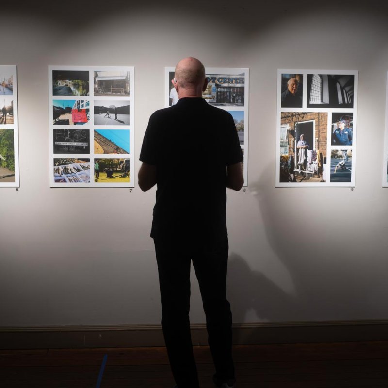 A man standing in front of a wall of photographs at Oxford House