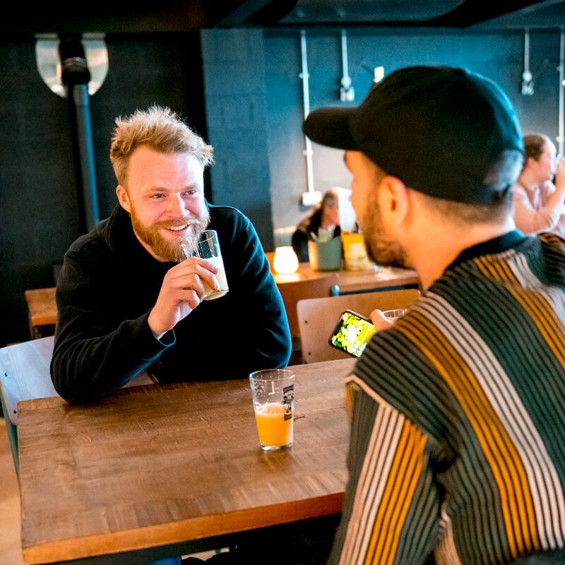 Two men sat at a table having a drink at Verdant Taprom