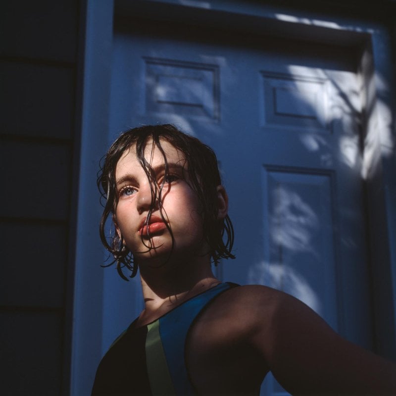 Photograph of a girl with dark wet hair with the sun on her face