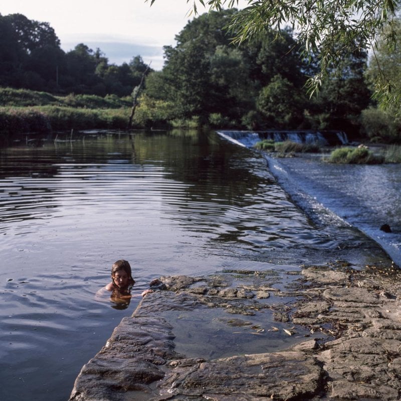 Photograph of a young girl swimming in a river
