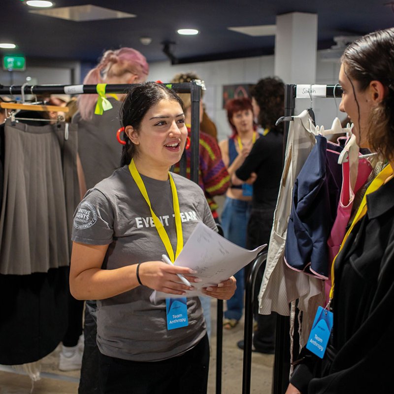 Events student holding paper and talking to someone