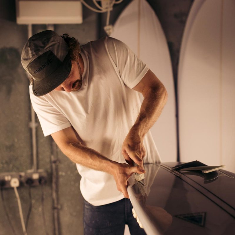 Photograph of a man putting fins in a surfboard