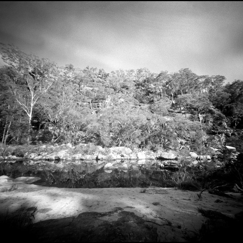 Black and white photograph of water, rocks and trees