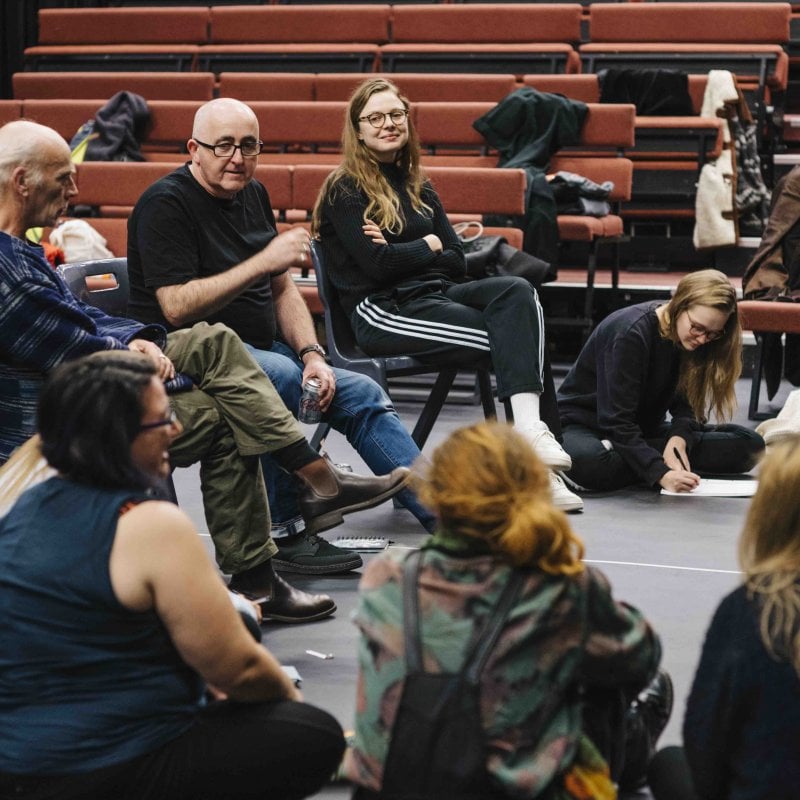 Group of acting students gathered in circle discussing