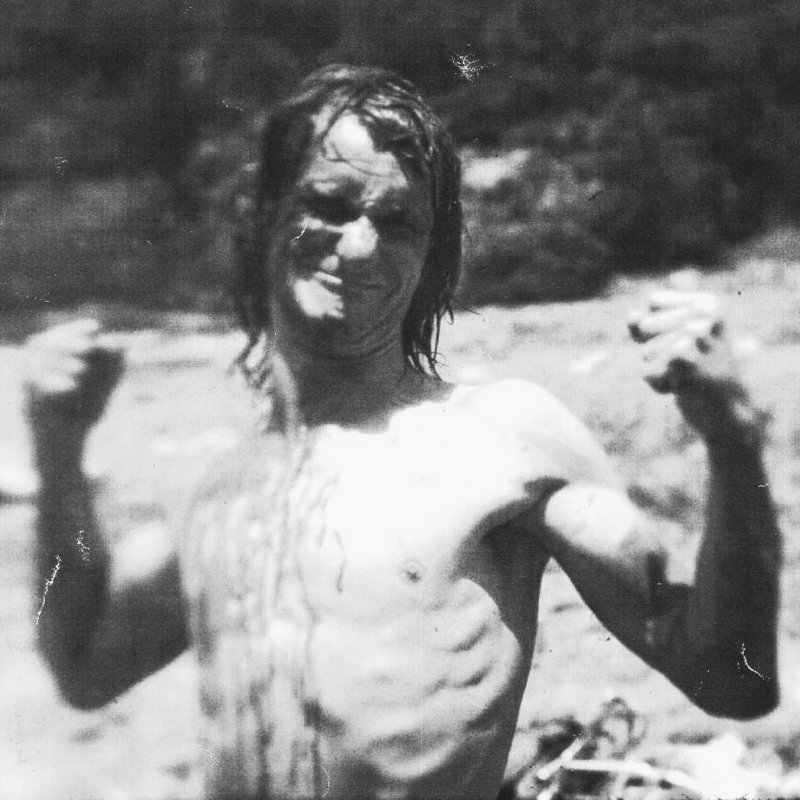 Black and white photo of a topless man pulling a funny face