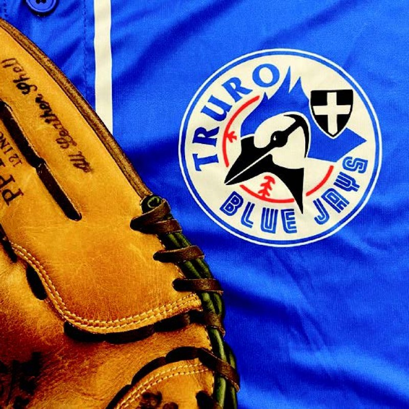 Logo of Truro Blue Jays on a blue shirt with a brown baseball mit