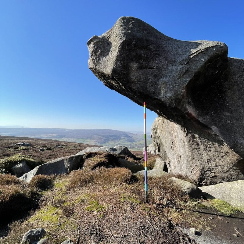 A pole sculpture underneath a rock on moorland 