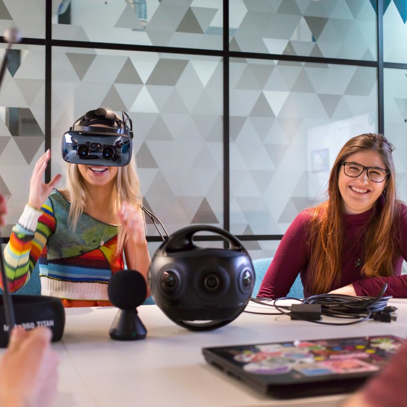 Two Falmouth University students at a table, one wearing a VR headset