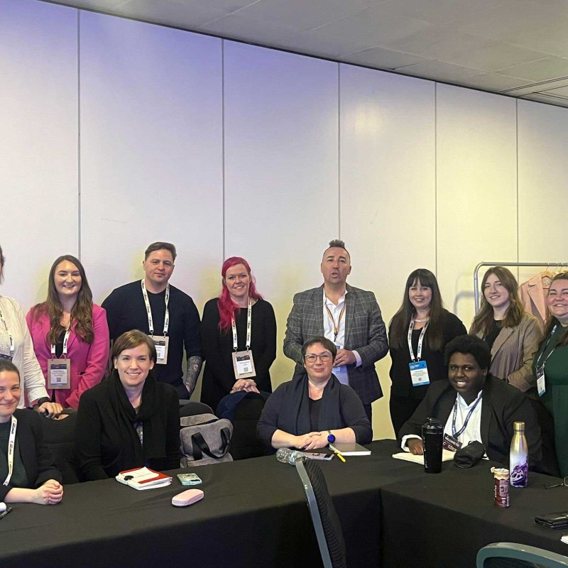 A group of students and staff sat at a table at a conference