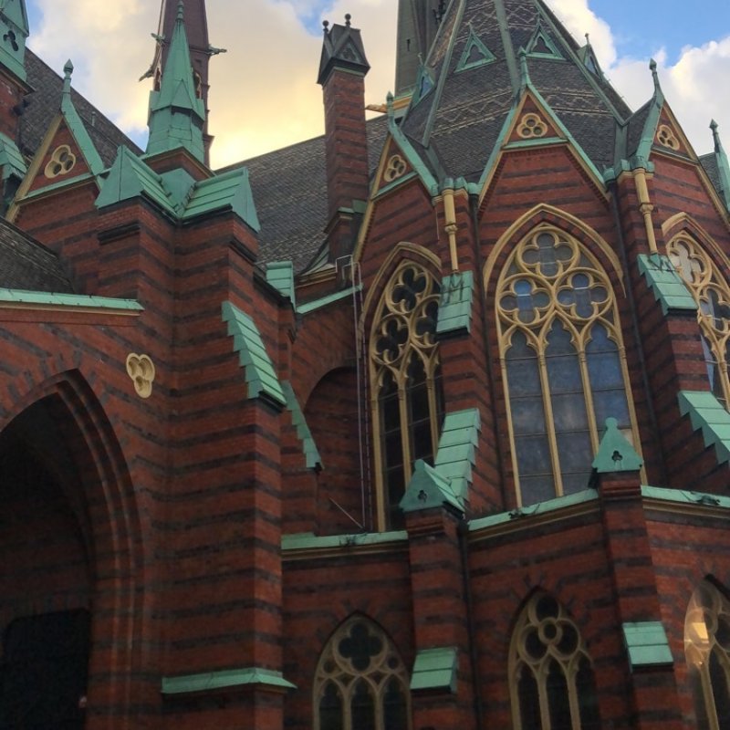 Photo of church in Sweden - red and black brick work with greened copper and gold details