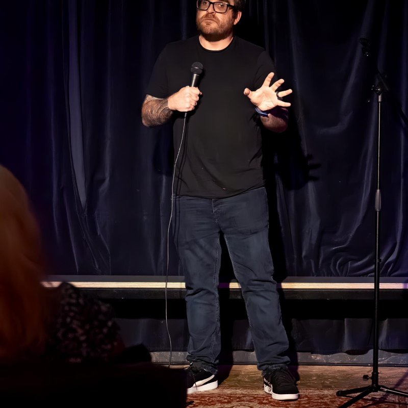 A man stood on stage performing a stand-up comedy routine