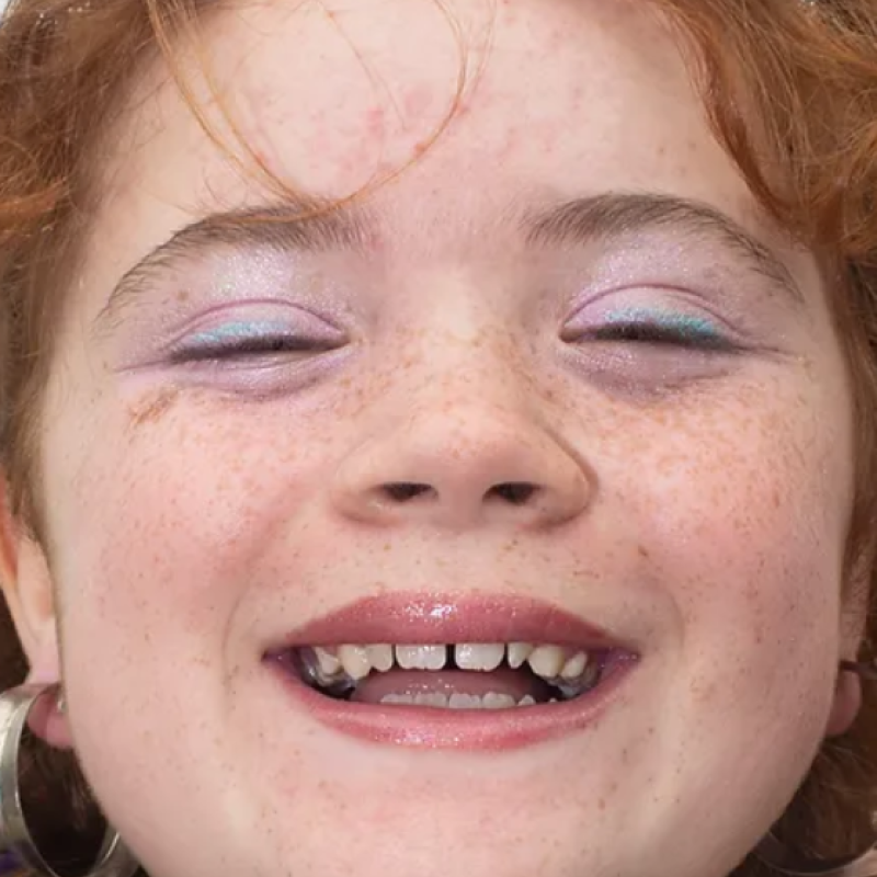 Close-up of smiling Cornish girl with ginger hair wearing makeup and a tiara - from Cornish Maids photography project by Fran Rowse