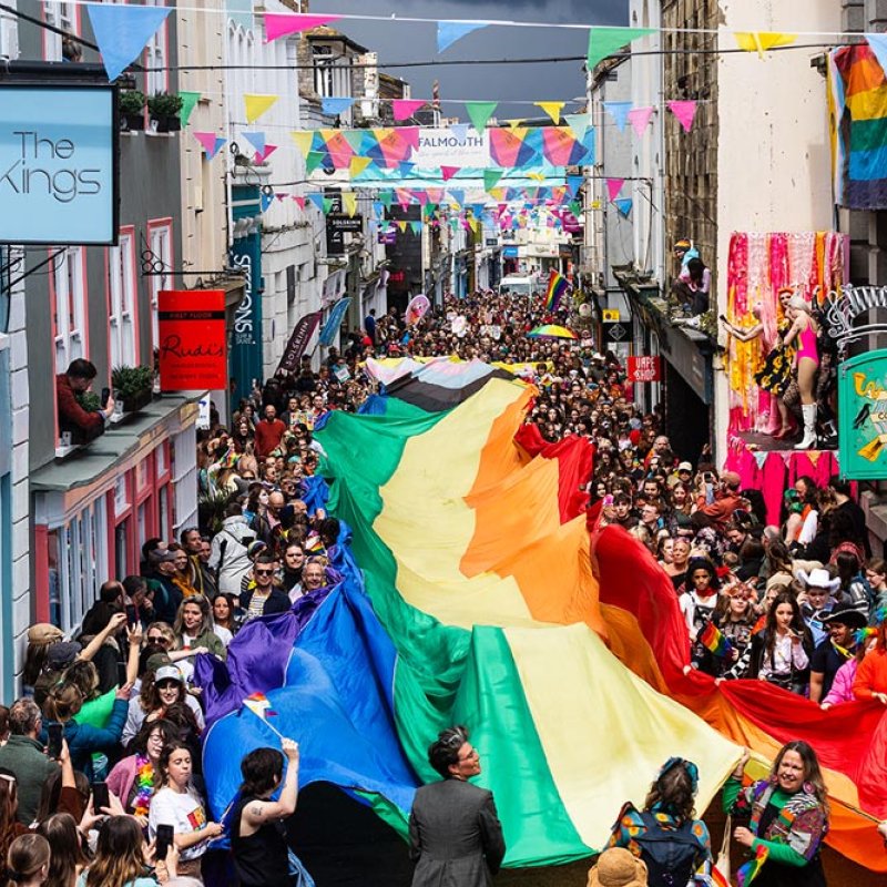 Falmouth high street with LGBTQ+ flag and crowd of people