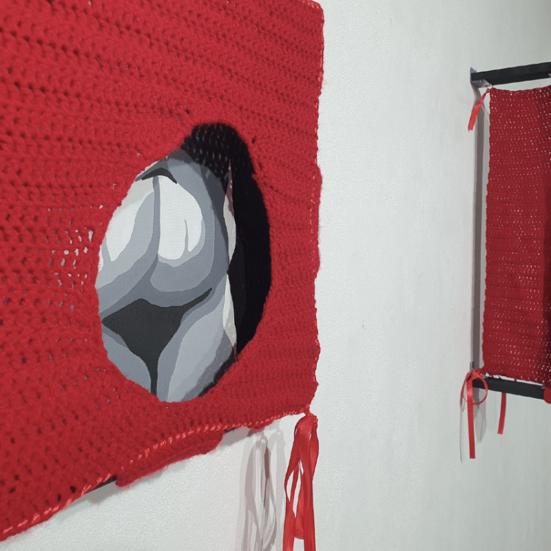 Red textile works hanging in a gallery