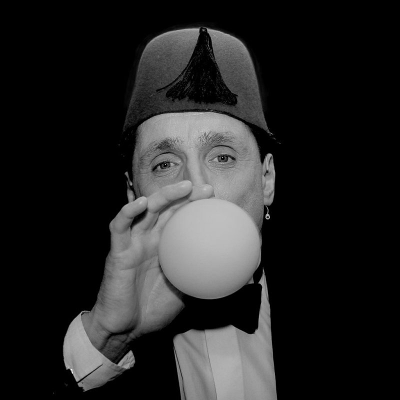 Black and white photography of a man blowing up a balloon