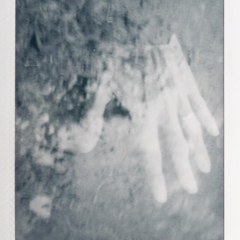 Polaroid of a hand overlaid with the ground