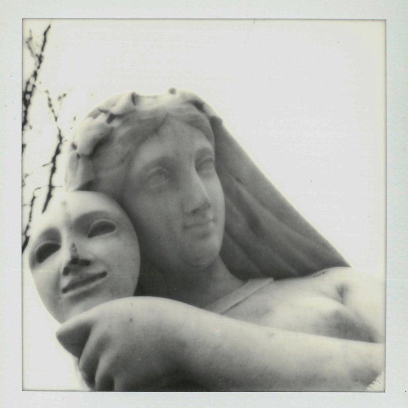 Polaroid of a marble sculpture woman holding a mask