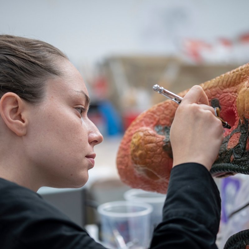 A close up shot of Camille painting her dinosaur design