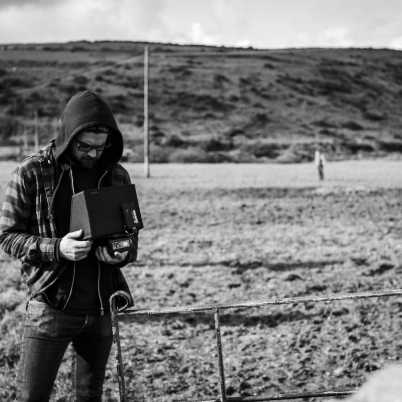 Ryan Mackfall looks into a camera on the set of Backwoods, pictured here standing in a field