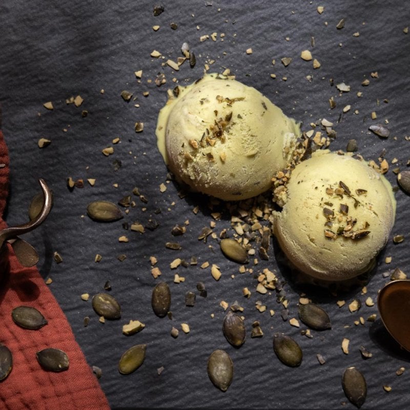 Two balls of ice cream with seeds, spoon and red fabric
