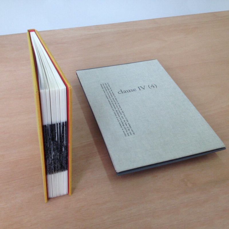 Hand bound book stood upright and grey cloth rectangle with type laid next to it.