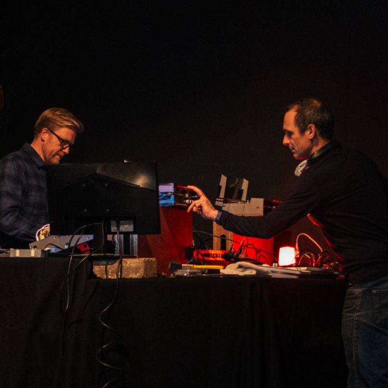Two men on a stage using analogue equipment to perform a live film score