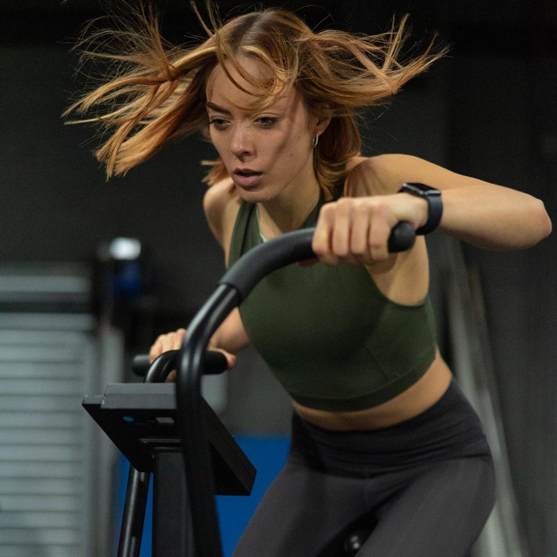 A woman on a cross trainer wearing leggings and sports bra