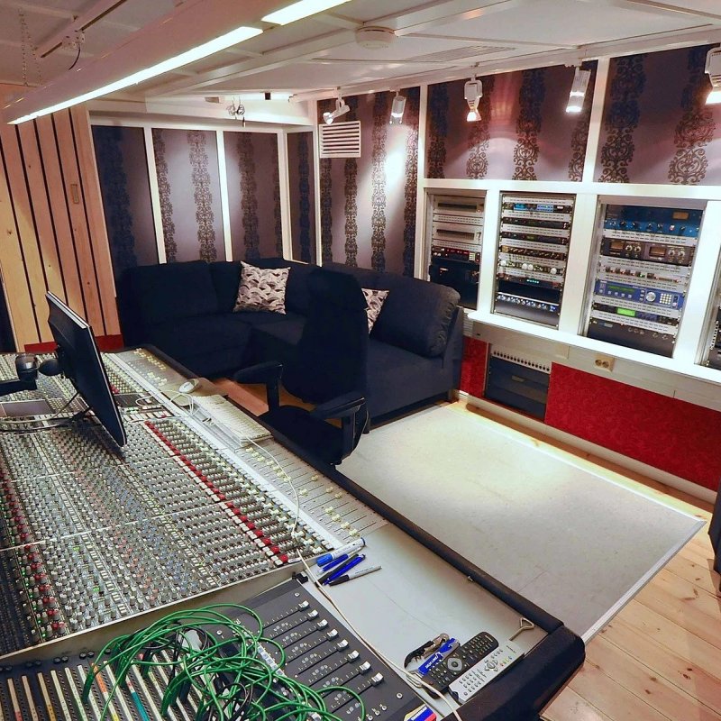 An empty recording studio - an enormous control panel can be seen, with sofas positioned in either corner of the room