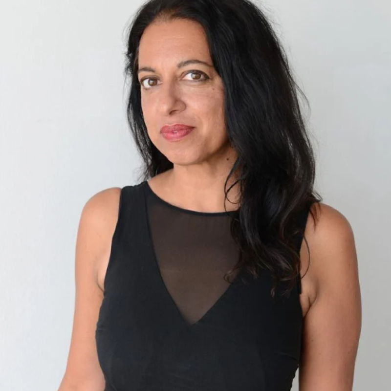 A woman wearing a black dress smiling into the camera