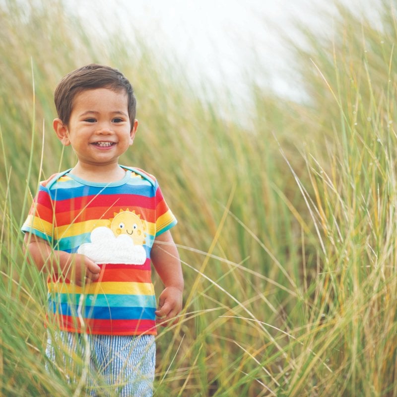 A boy wearing a multi-coloured shirt in a field