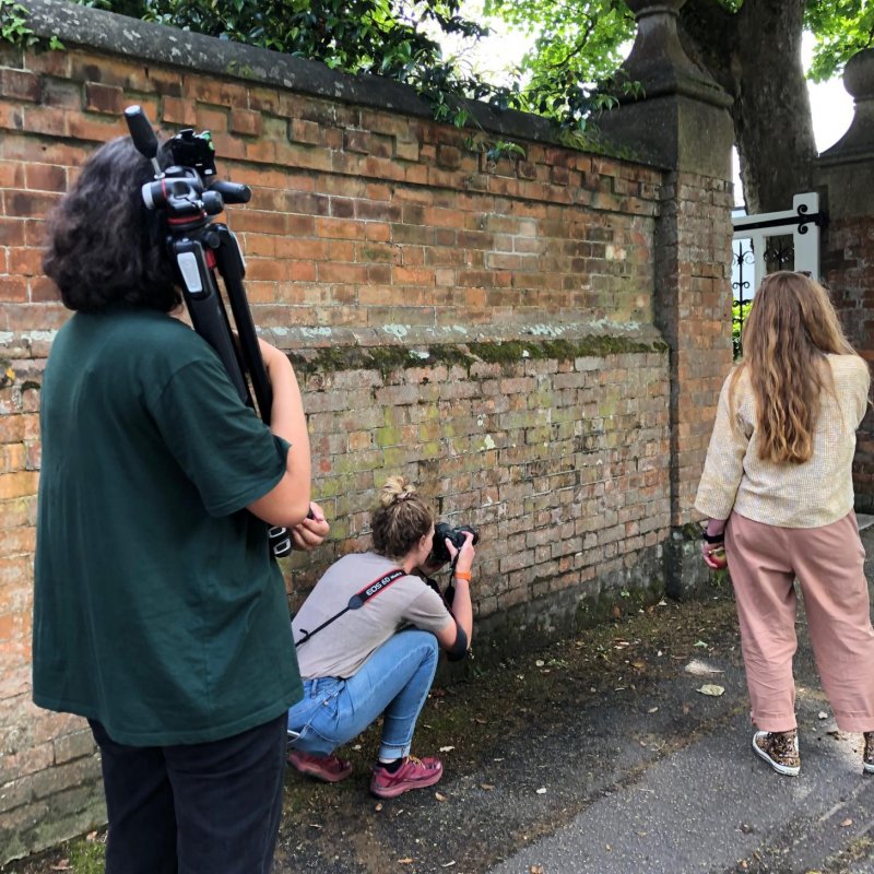 A woman carries a tripod, as another woman takes photographs