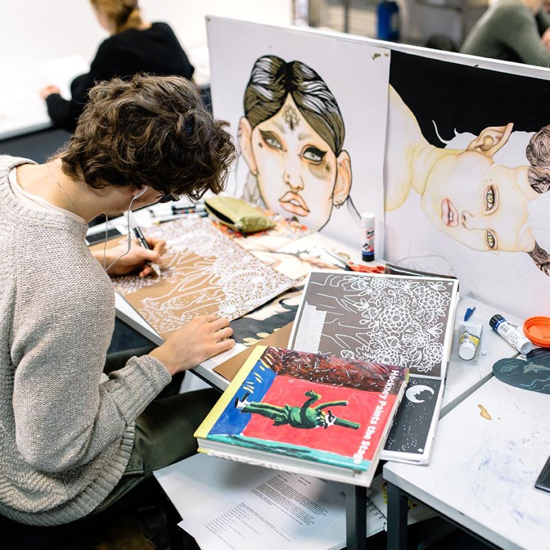 Male student drawing at a desk
