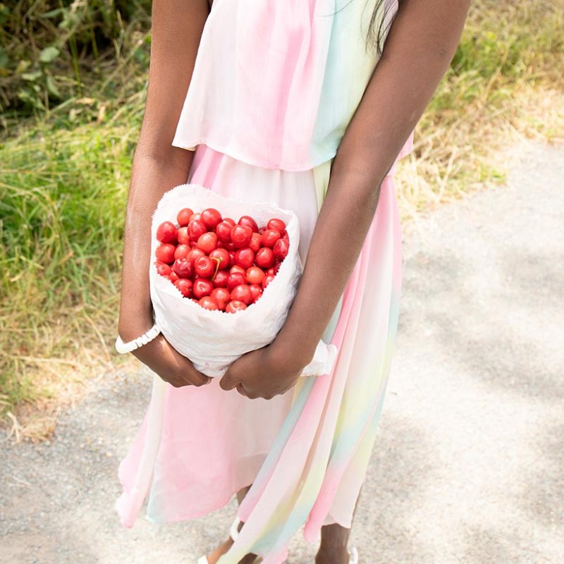 Photograph of a woman holding a bag of red cherries