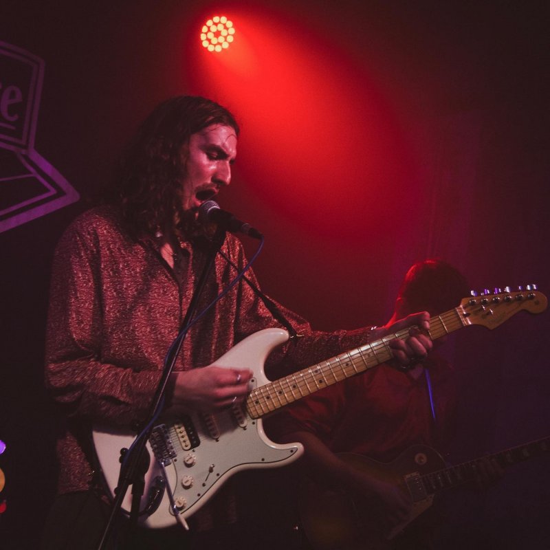 A man playing the electric guitar is singing into a microphone