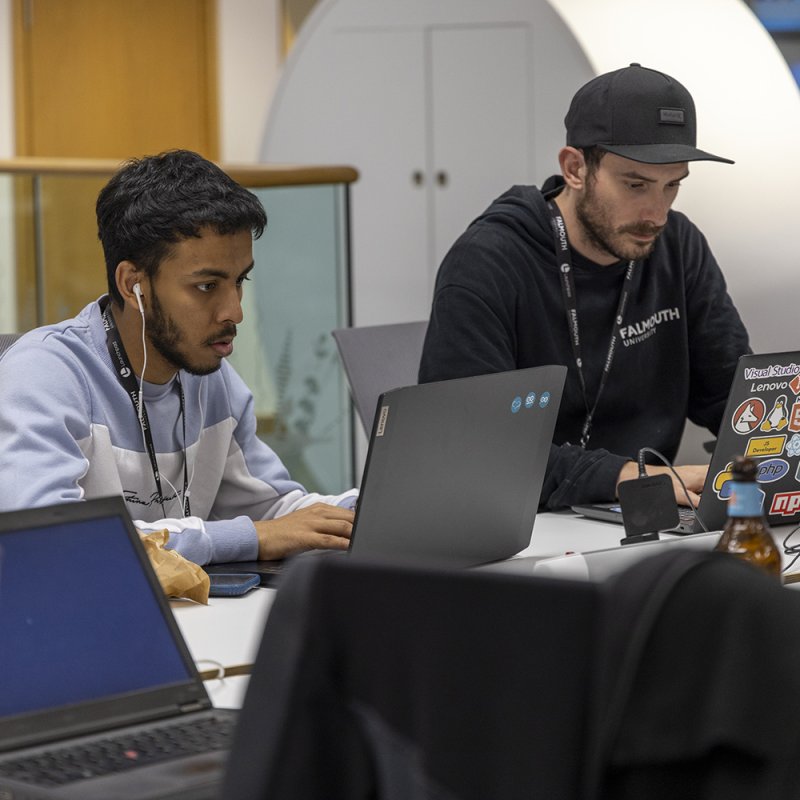 Two student sat working at laptops