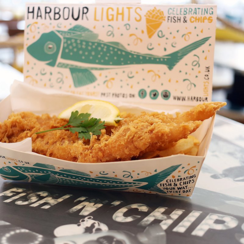 A box full of fish and chips with lemon and parsley