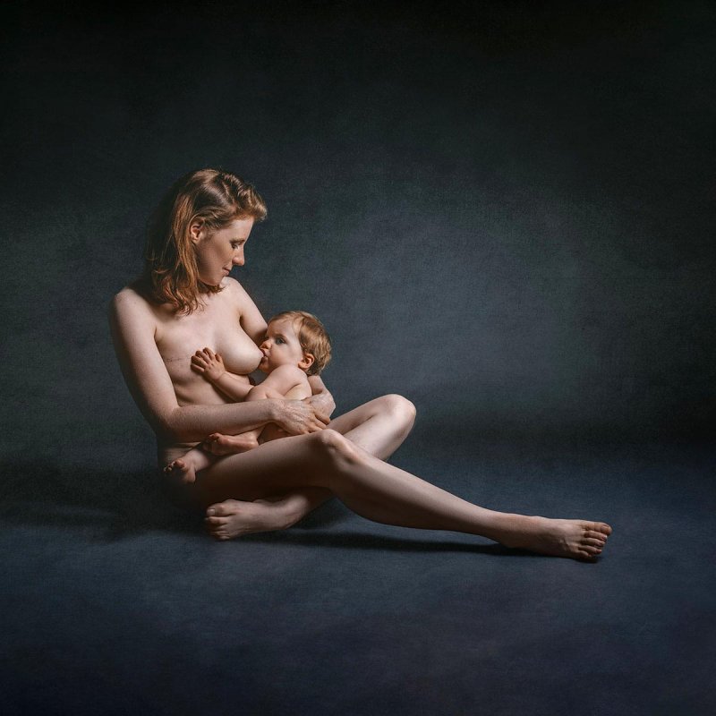 A nude mother breastfeeding her young child