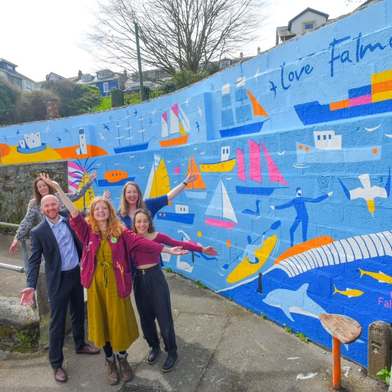 Five people next to the Love Falmouth mural