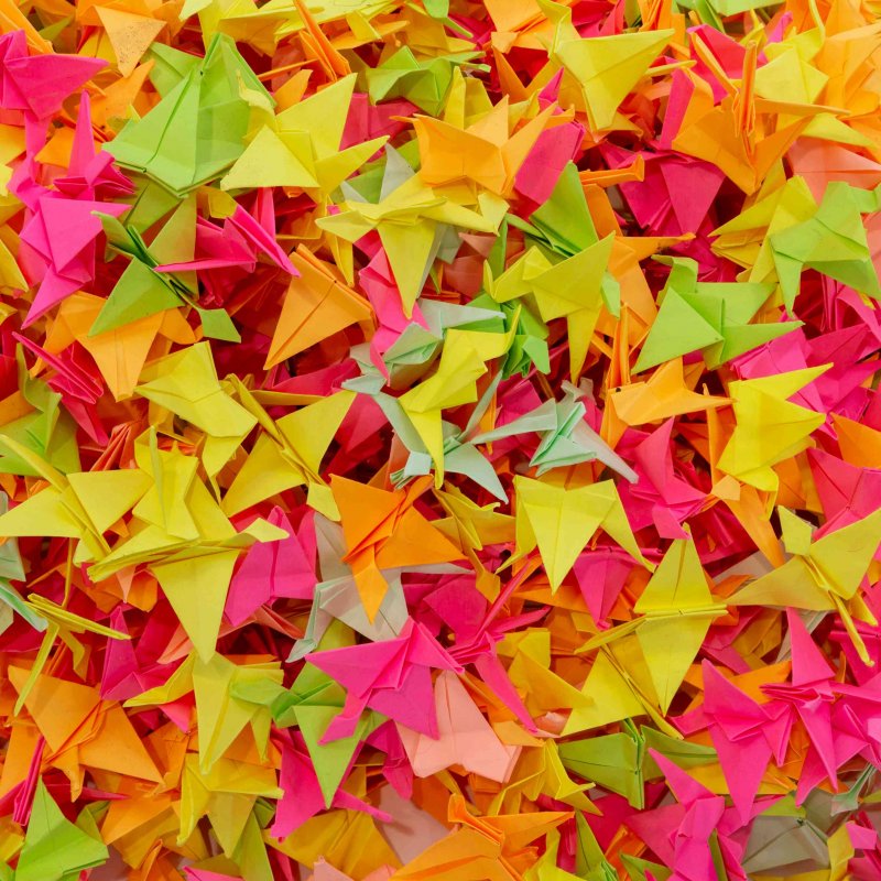 A large pile of origami birds in several colours 