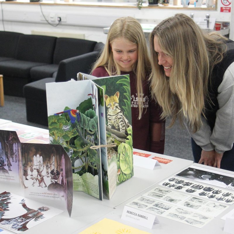 A mum and a daughter looking at work by Illustration students