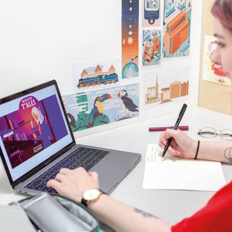 Student looking at laptop and drawing