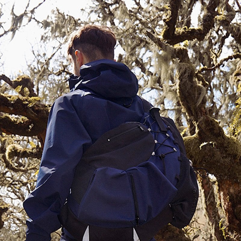 A man wearing a blue coat and bag designed by Falmouth University Fashion student