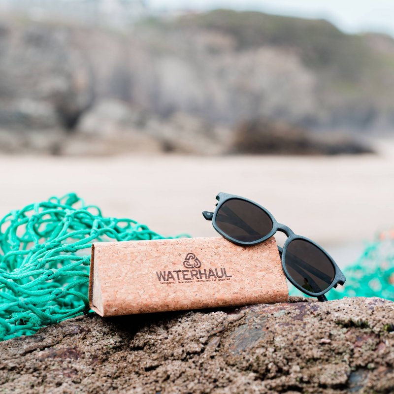 A pair of sunglasses are balanced on a bamboo box, with a fishing net in the background